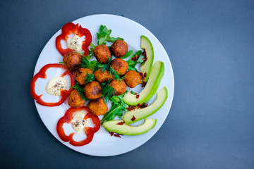 Vegetarian falafels and vegetables on a plate. With pepper and herbs and avocado