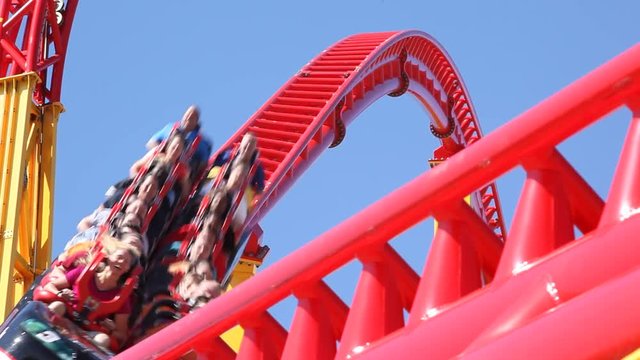 People ride a rollercoaster at an amusement park.
