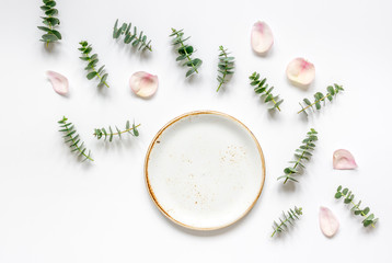 Mock up with rose petals and eucalyptus on white table top view