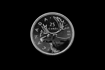 A close up image of an old Canadian quarter on a black background