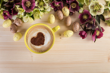Obraz na płótnie Canvas Coffee cup Cappuccino with Easter decoration on light wooden table. Heart shape foam, top view.