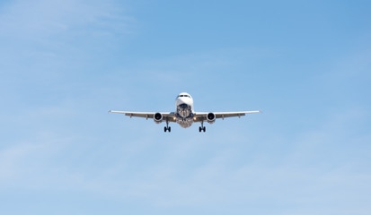 Fototapeta na wymiar Commercial airplane flying in blue sky, full flap and landing gear extended