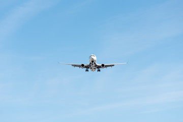 Commercial airplane flying in blue sky, full flap and landing gear extended