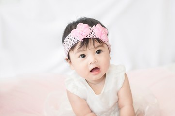 Portrait of cute baby girl in white dress on blanket of fur