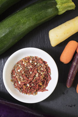 Zucchini and Carrots on a slate cutting board with a small bowl of spices
