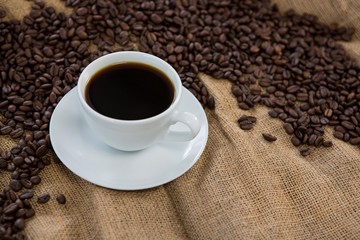 Coffee cup with coffee beans on sack