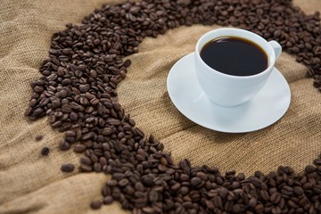 Coffee cup with coffee beans arranged on sack