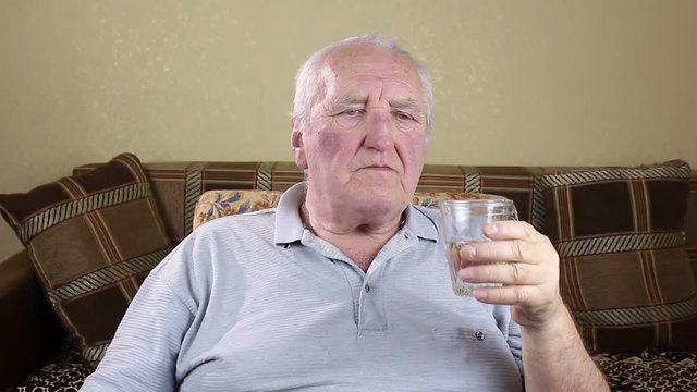 Elderly man drinking water from a glass.