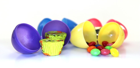 Assorted colored easter eggs open with assorted candy inside