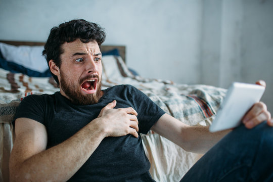 Portrait of a young man relaxing and watching a TV show on a tablet computer