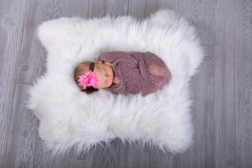 Newborn baby girl swaddled and sleeping on fur