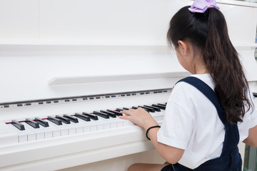 Asian Chinese little girl playing classical piano at home