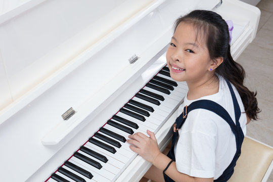 Happy Asian Chinese Little Girl Playing Classical Piano At Home