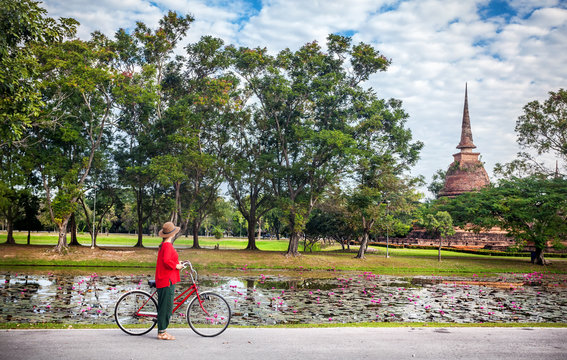 Woman with bicycle near temple in Thailand