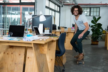 Graphic designer skating with skateboard in creative office © WavebreakMediaMicro
