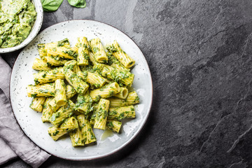 Vegetarian pasta with green avocado and herbs sauce pesto. Top view