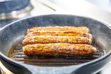 Sausage of beef fried in a skillet-grill.