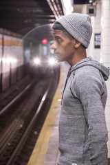 A young, black hipster waits for a NYC subway train