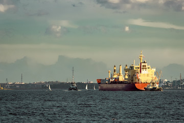 Red cargo ship and the tug ship towing  it to the port