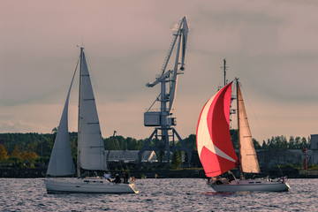 Sailboat regatta on Daugava river. Two yachts sailing past the c