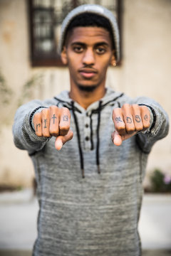 A young, black man shows off the tattoos on his knuckles - portrait