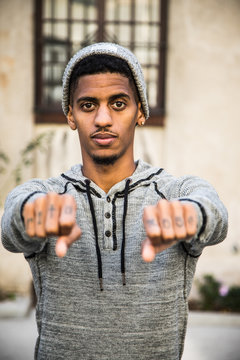 A young, black man shows off the tattoos on his knuckles - portrait
