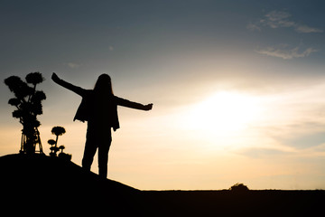 Fototapeta na wymiar woman silhouette standing raise hand on sunset