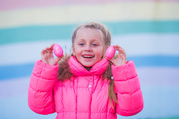 Cute pretty girl playing with colored eggs for Easter celebration