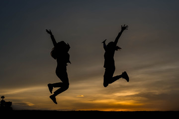 Silhouette woman jumping at sunset