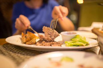 Girl eating meat with salad in a restaurant