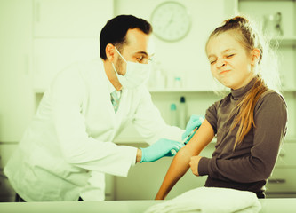 Male doctor injecting little patient