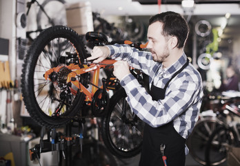 Fototapeta na wymiar Mechanic in bicycles store workshop