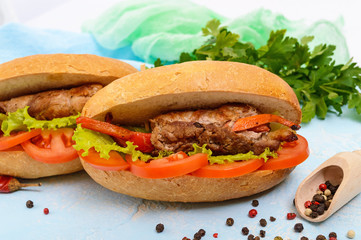 Sandwich: Meat rolls with vegetables in a bun with tomato and lettuce leaves.