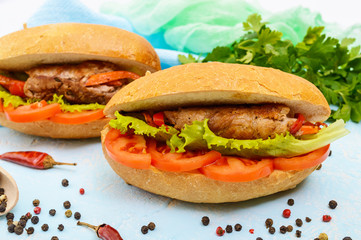 Sandwich: Meat rolls with vegetables in a bun with tomato and lettuce leaves.