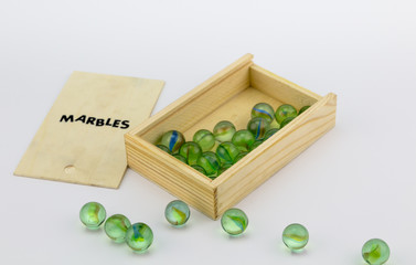 Wood box of green glass marbles on white background