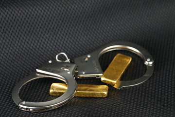 The chrome metal handcuffed and gold bar represent the crime fraud and punishment equipment concept related idea.
