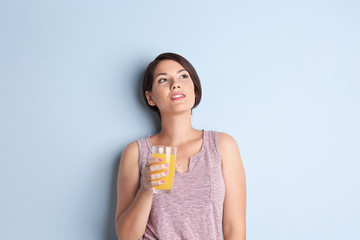 Young beautiful woman with glass of orange juice, on light background