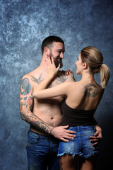 Passion tattooed beautiful couple on gray wall background