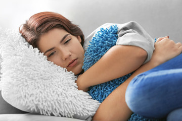 Obraz na płótnie Canvas Depressed young woman lying on sofa at home, closeup