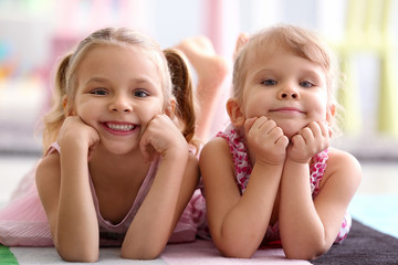 Adorable little sisters lying on the floor at home