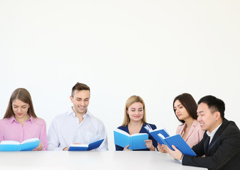 Group of people reading books while sitting at table