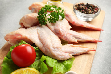 Raw chicken wings with spices on cutting board