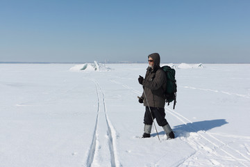 Nordic Walking - adult man with a backpack hiking  on snow in winter