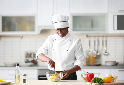 Mature Indian chef cooking in kitchen