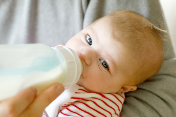 Father feeding newborn baby daughter with milk in nursing bottle
