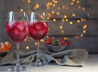 Glasses of delicious wine spritzer on blurred lights background