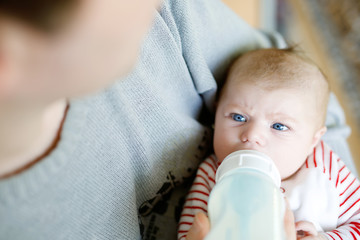 Father feeding newborn baby daughter with milk in nursing bottle