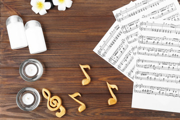 Fototapeta na wymiar Composition of music sheets and spa supplies on wooden background