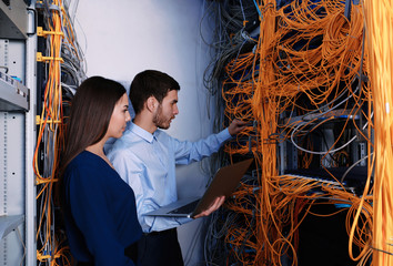 Young engineers connecting cables in server room