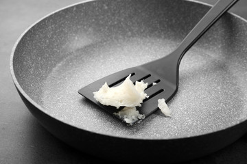 Spatula with coconut oil on frying pan
